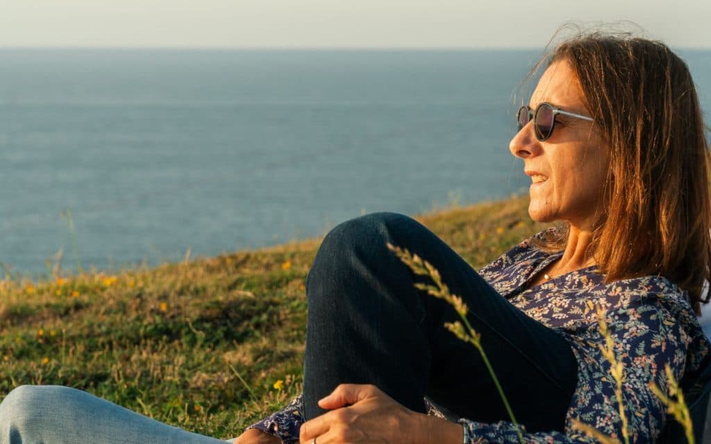 Woman sitting by the ocean in a calm, reflective moment during arterial dissection recovery